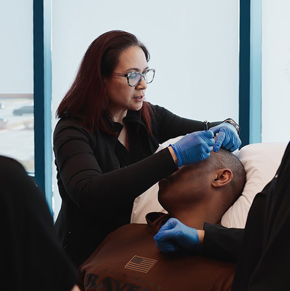Provider performing a dermatologic procedure at Urbana Dermatology